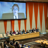 در تصویر، نمای عمومی از سالن مقر سازمان ملل در نیویورک و صفحه بزرگ ویدئو بر روی دیوار دیده می‌شود که در آن جاوید رحمان، گزارشگر ویژه حقوق بشر در ایران، در حال سخنرانی است.