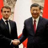 شی جین‌پینگ، رئیس جمهوری چین و امانوئل مکرون، رئیس جمهوری فرانسه پس از دیدار در پکن با لبخند دست یکدیگر را فشرده‌اند. پرچم‌های چین و فرانسه پشت سر آن‌ها دیده می‌شود.