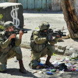 دو سرباز اسرائیلی روی زمین زانو زده‌ و با تفنگ‌های خود به سمت هدف نشانه گرفته‌اند.